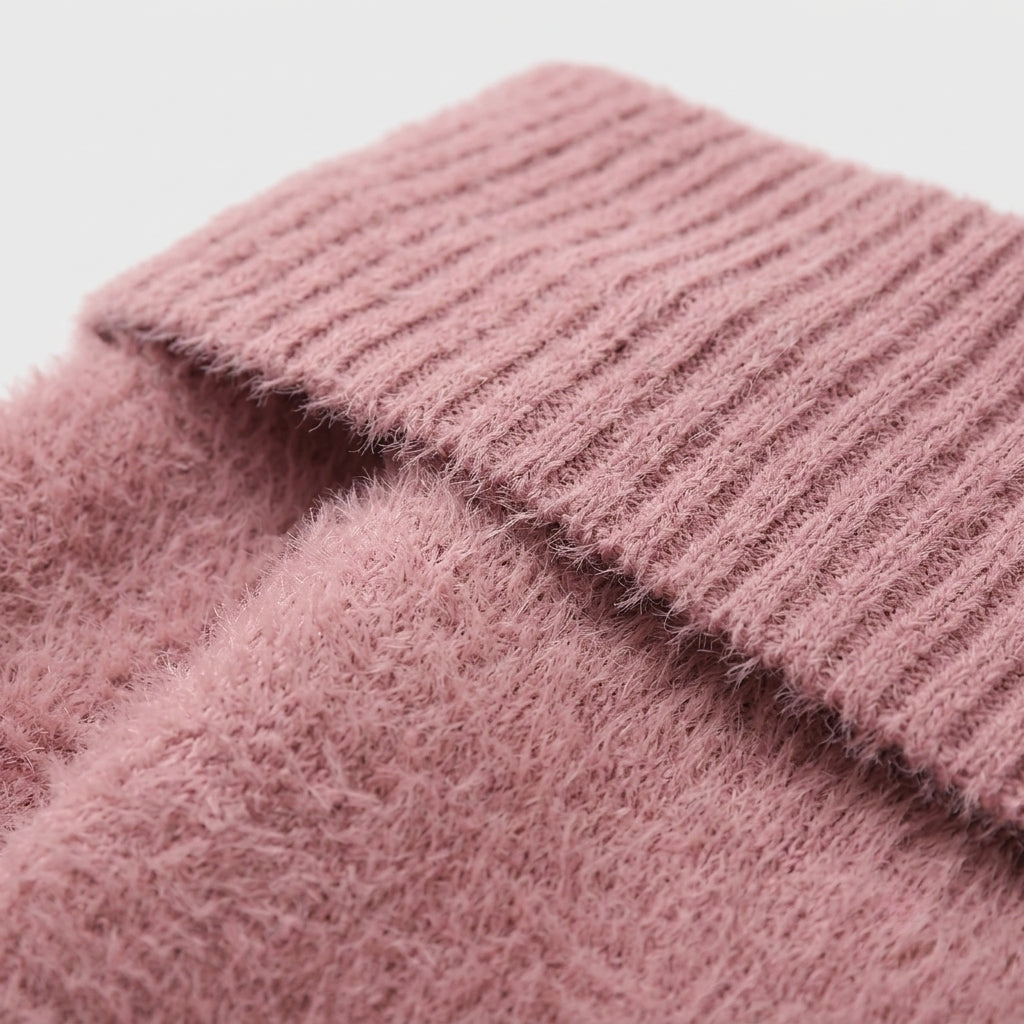 Close-up of a dusty pink fuzzy knit fabric with a ribbed cuff, showing the soft textured material against a light neutral background.