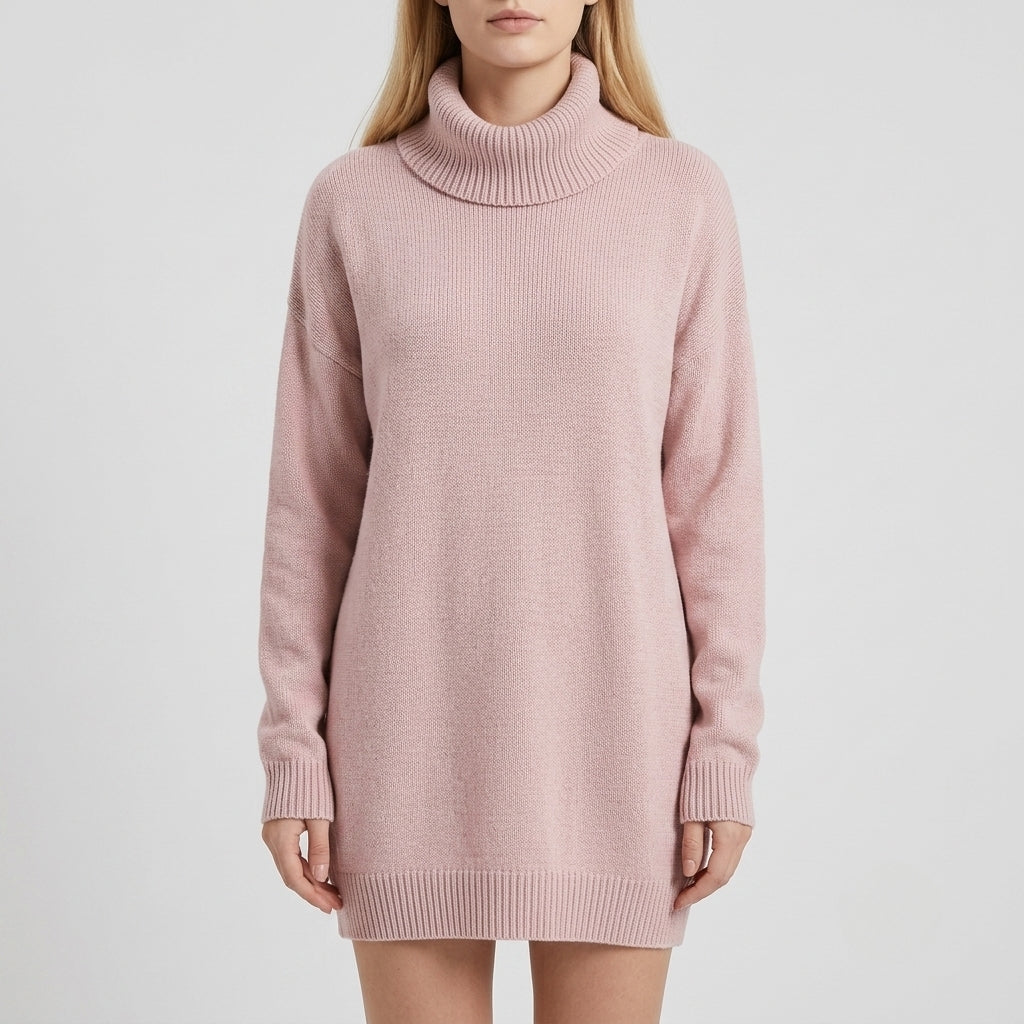 A woman wearing a light pink ribbed knit turtleneck sweater dress, shown from the neck down against a plain light gray studio background.