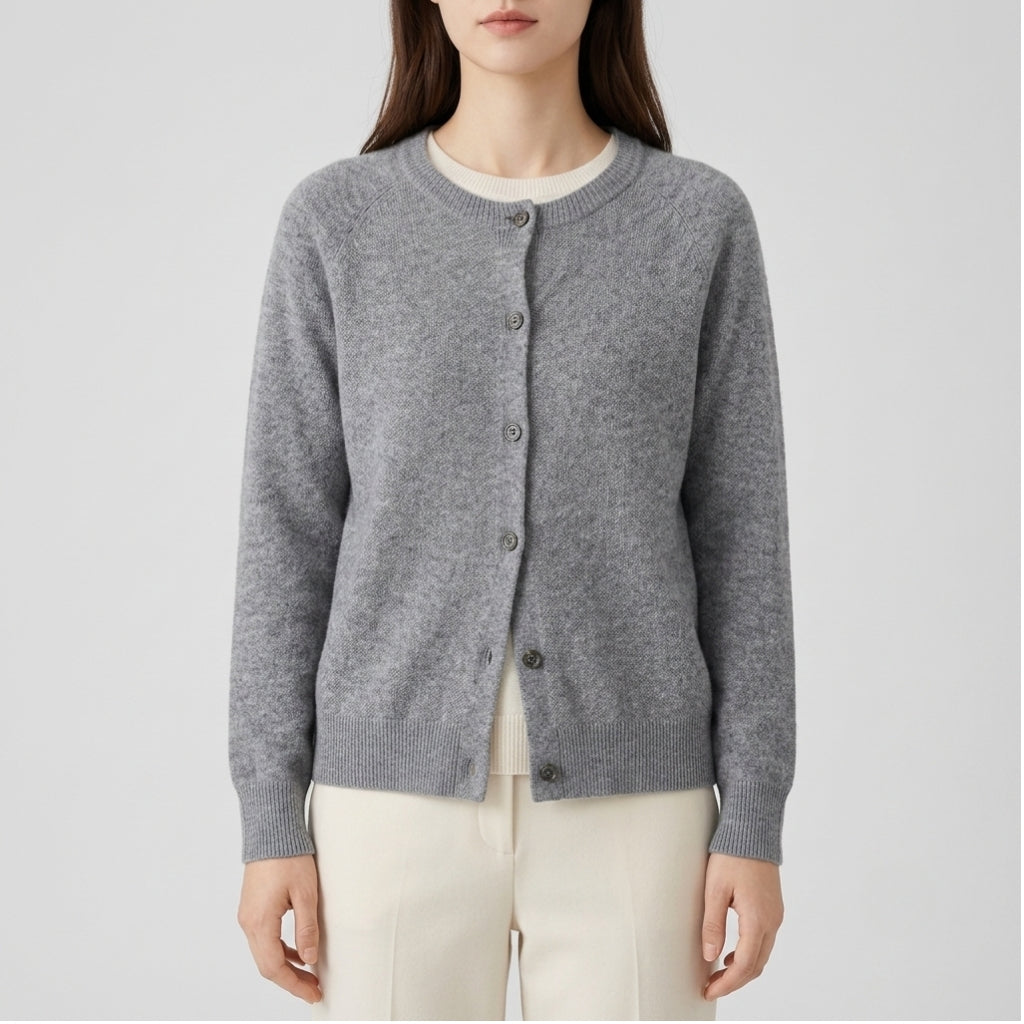 A woman wearing a heather gray button-up cardigan sweater over a cream crewneck top and cream pants, shown from the neck down against a light gray studio background.